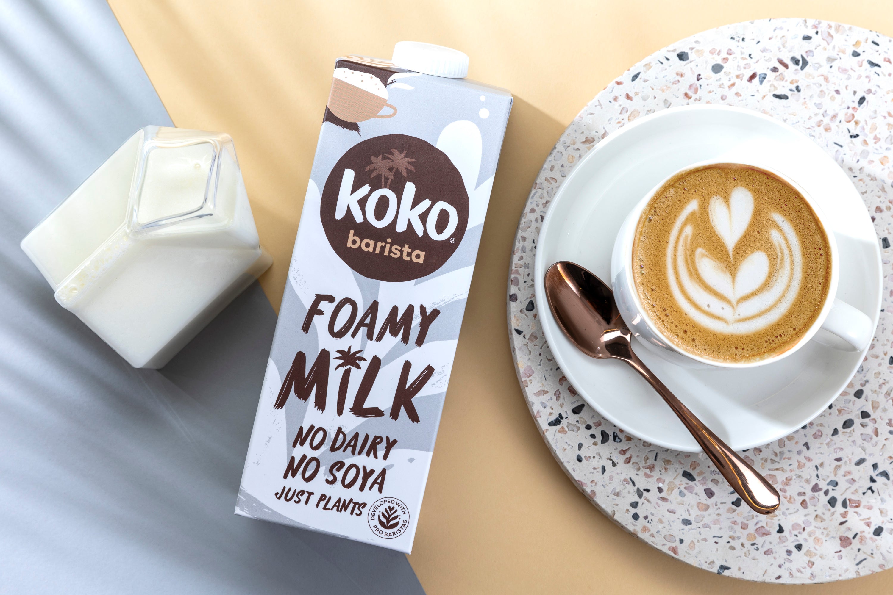 Koko Barista UHT milk in cappuccino cup with foam art, lifestyle setting.