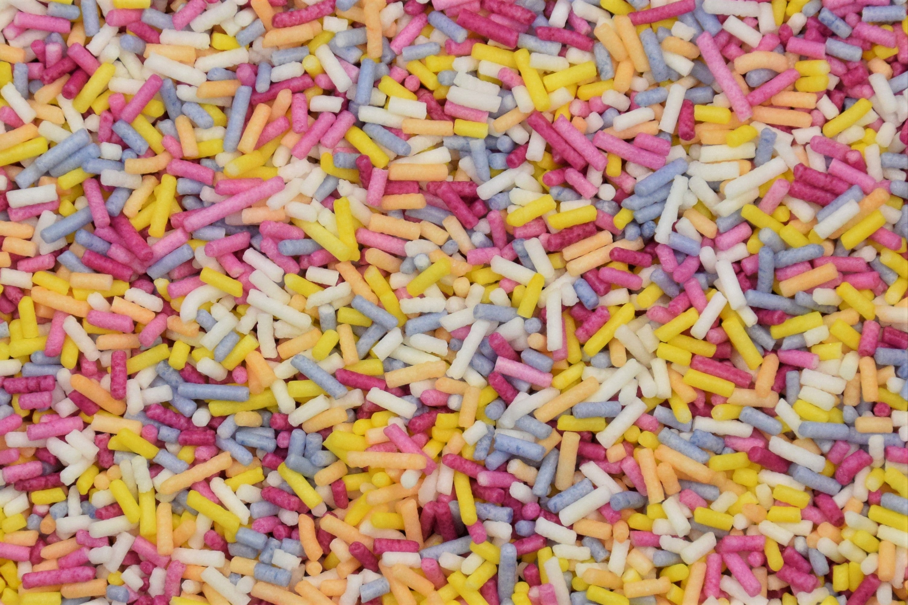 A tub of rainbow sprinkles spilling onto a surface