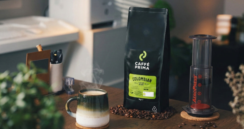 a bag of Caffe Prima  Colombian coffee beans on the table next to the aeropress