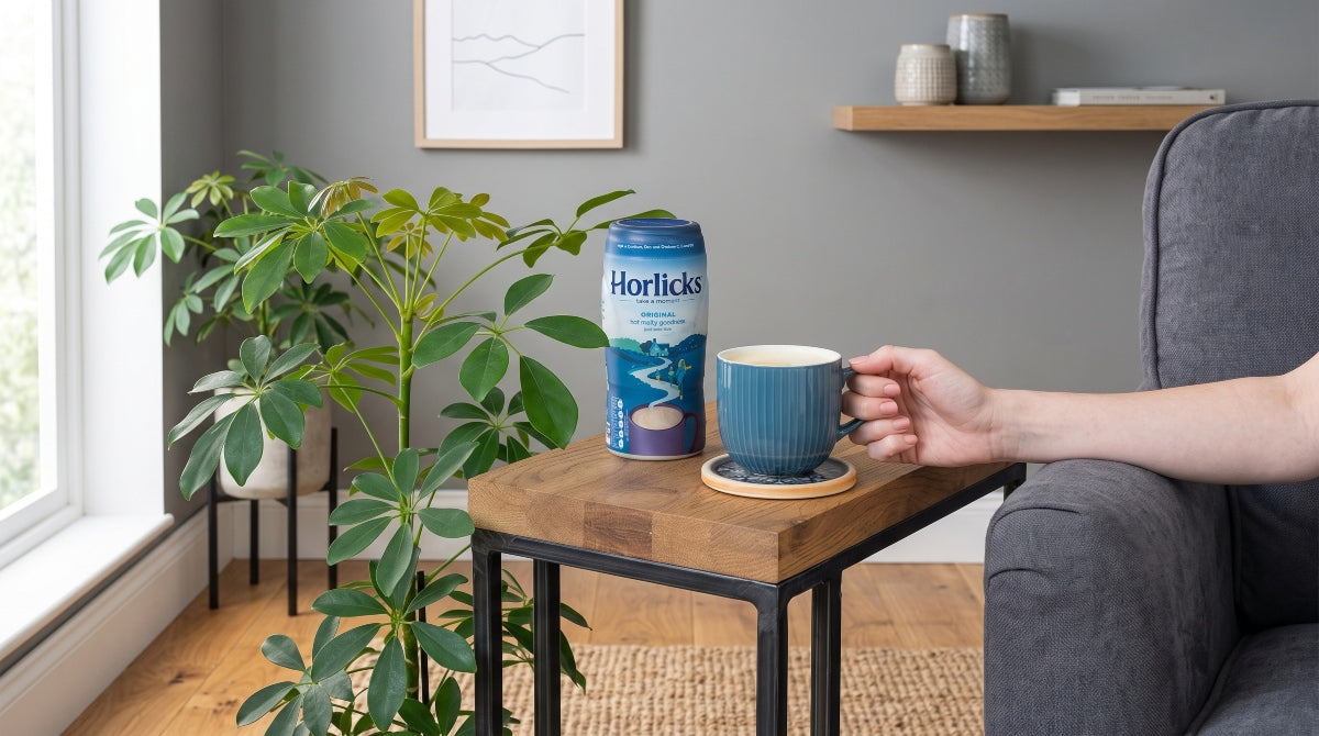 a tub of horlicks and a mug with a drink on the coffee table