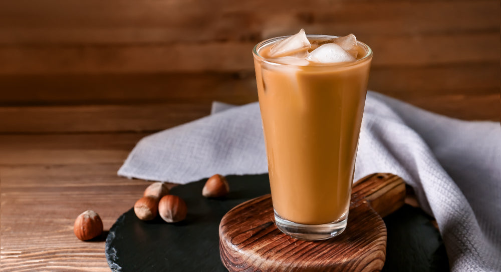 a glass of iced coffee served on a wooden tray in a cafe