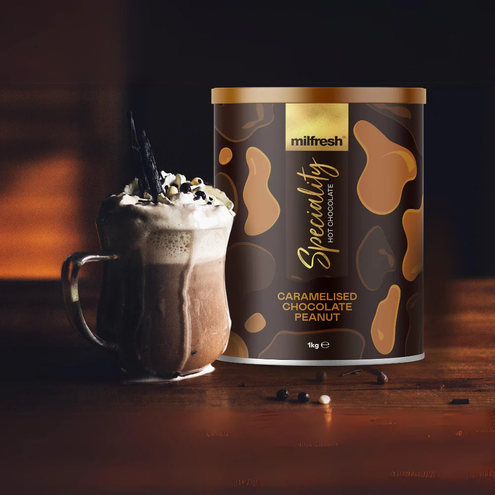 A tub of 1kg Milfresh Speciality Peanut on tabletop with hot chocolate in mug
