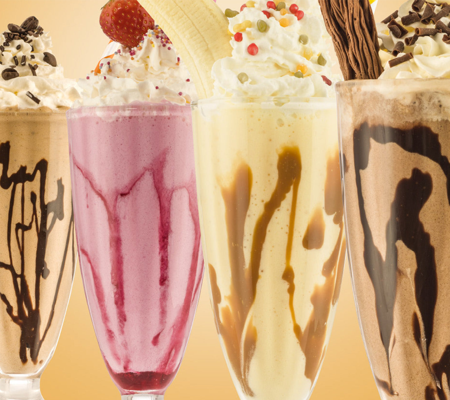 four glasses of deluxe milkshakes in a row, chocolate, strawberry, vanilla and chocolate